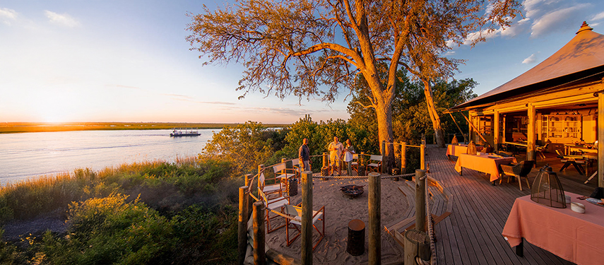 Guests talk to a guide on the deck of Little DumaTau tented safari camp