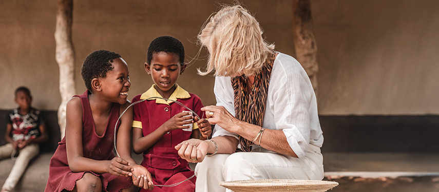 Guest engages in craft-making with two local children as part of a community visit experience.