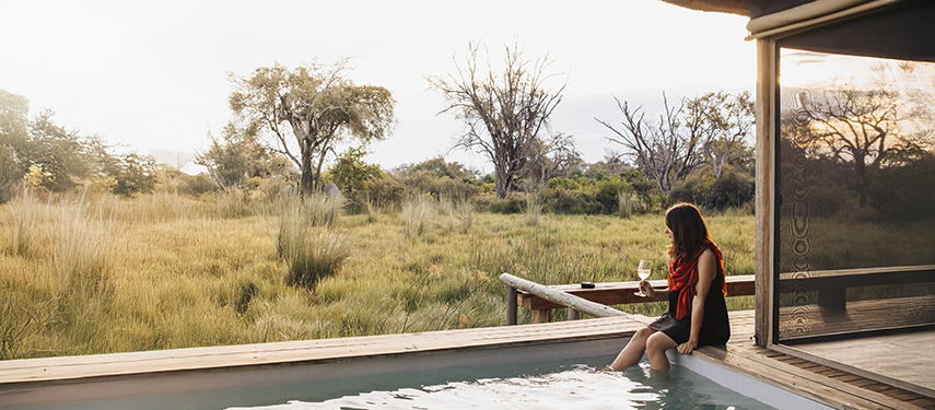 Guest looks out over the grassy plains from Vumbura Plains safari lodge in Botswana's Okavango Delta