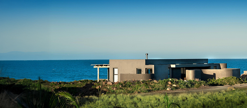 Exterior view of a modern suite at Gwegwe Beach Lodge with ocean backdrop.