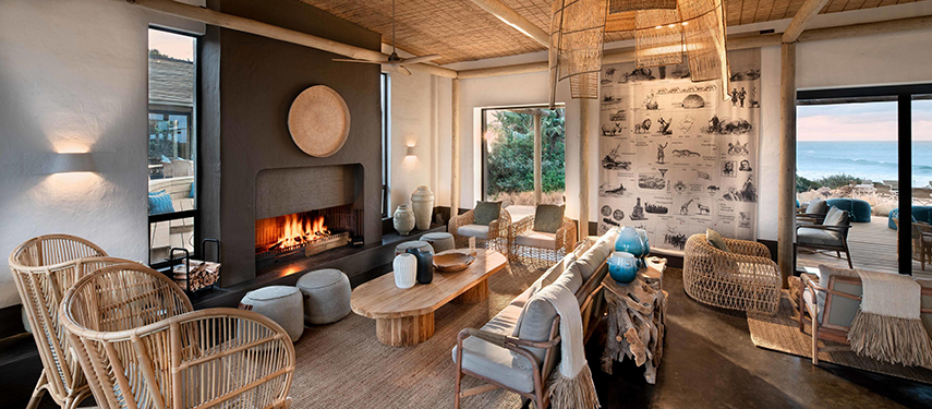 Cosy lodge lounge with a fireplace and elegant décor, overlooking the ocean.