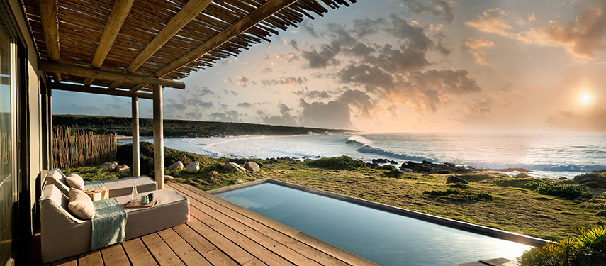 Private deck with plunge pool overlooking the beach and ocean at sunset.