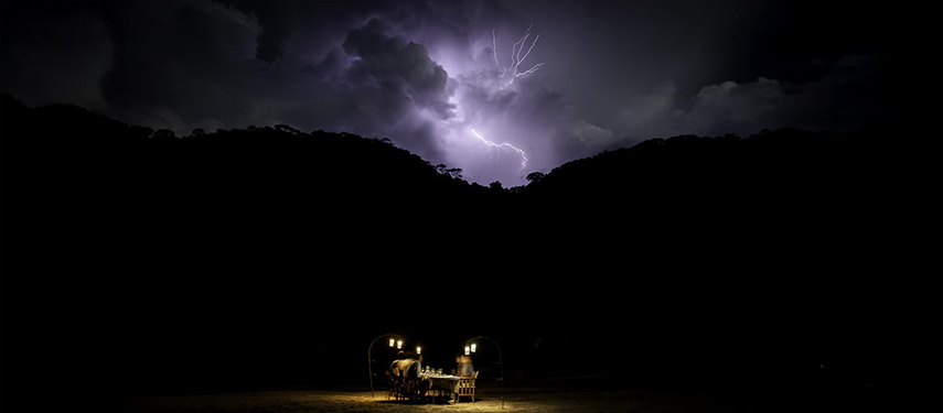 Lamplit dinner in Africa with lightning in the background