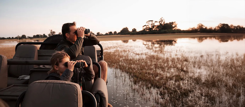 Tourists view wildlife with binoculars on a game drive in the Linyanti region of Botswana