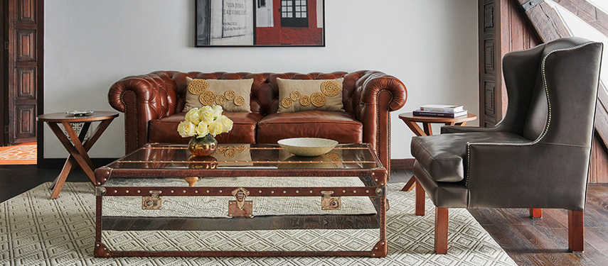 Stylish lounge area at Four Seasons Casa Medina featuring a vintage leather chesterfield sofa, glass trunk coffee table, and classic décor elements.