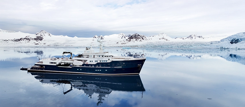 Aqua Lares reflected in still polar waters beneath vast glaciers and a pale Arctic sky.