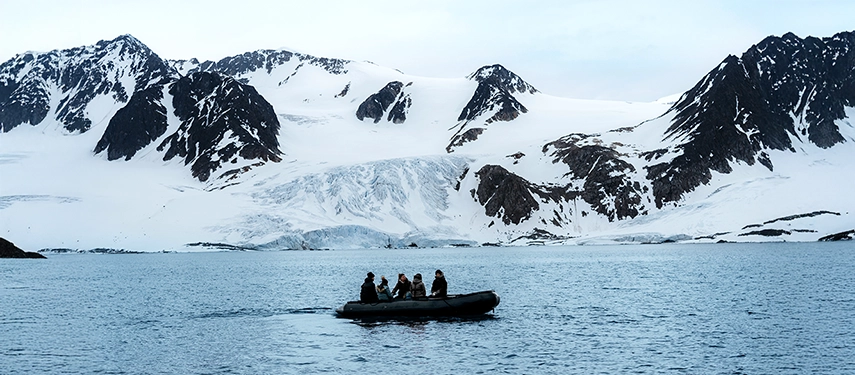 Travellers in a Zodiac exploring dramatic snow-covered mountains and icy cliffs.