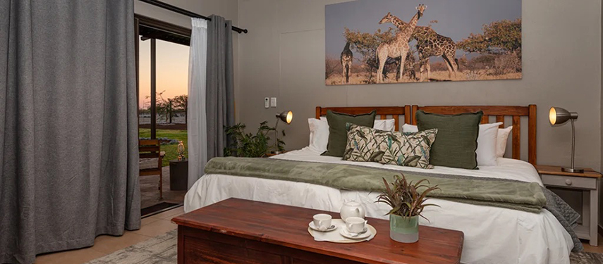 A warmly lit Safari House bedroom with double bed, wooden furnishings, and wildlife-themed decor.