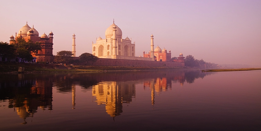The Taj Mahal at sunrise reflected in the Yamuna River, capturing the serene symmetry of India’s most celebrated Mughal monument in Agra. 