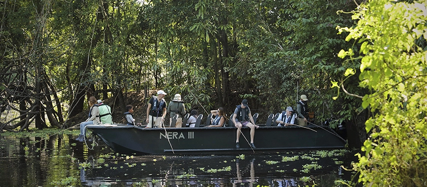 Guests aboard a skiff named Nera III exploring flooded forest waterways on an Amazon excursion.