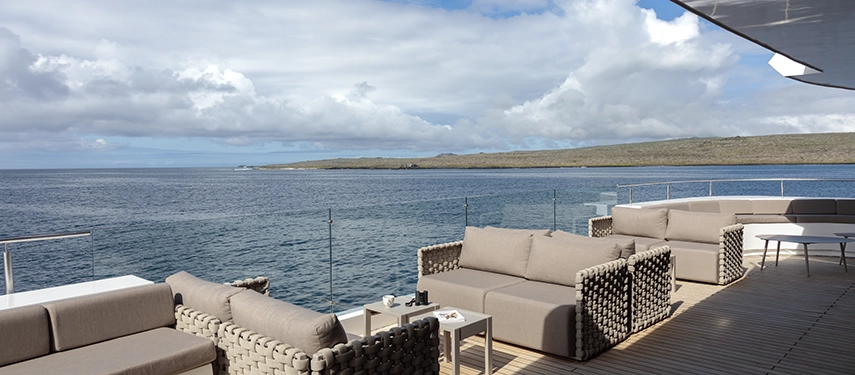 Outdoor lounge with cushioned seating and ocean views on the Hermes Galápagos Mega Catamaran.