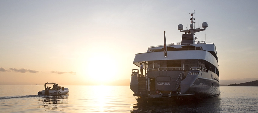 Aqua Blu rests quietly in a deep blue bay surrounded by emerald islands and mirrored reflections on the still water.