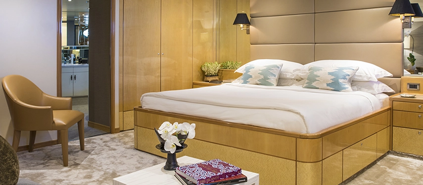 Spacious cabin with refined neutral interiors, king bed and cosy seating, accented by warm wood details and soft natural light.