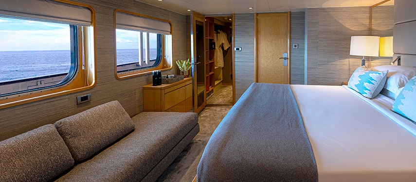 Stylish suite with textured walls, ocean-facing windows and modern comforts, blending understated elegance with panoramic sea views.