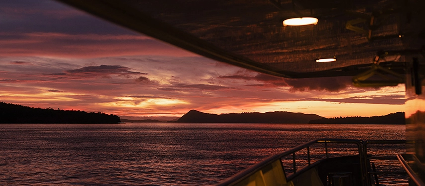Vibrant sunset over calm ocean waters viewed from Aqua Blu’s deck, hues of crimson and gold filling the horizon.