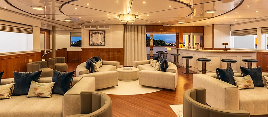 Elegant onboard lounge with curved sofas, rich timber floors and soft ambient lighting.