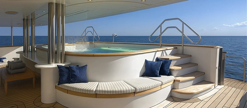 Curved Jacuzzi surrounded by cushioned seating on a teak deck under clear skies.