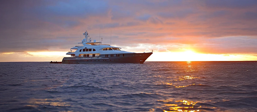 Aqua Mare glides across the ocean at sunset, her sleek lines illuminated by warm light against the horizon.