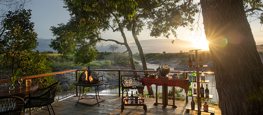 A sundowner setup with drinks and fire pit overlooking the river at sunset.