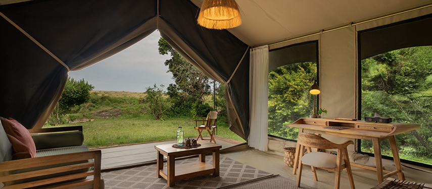 Lounge area of a guest tent with armchairs, coffee table, and wide views of the surrounding bush.