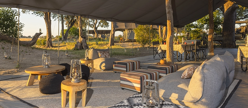 Shaded mess tent lounge with comfortable chairs, lanterns, and a view of the surrounding bush.
