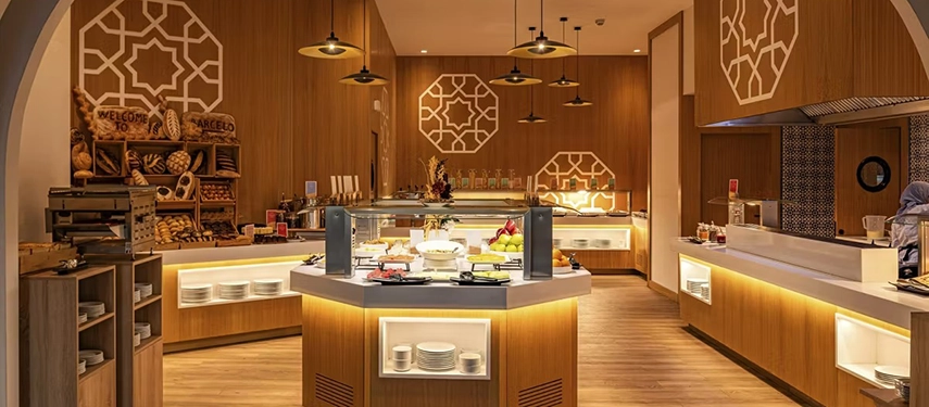 Bright buffet restaurant with wooden décor, geometric patterns on the walls, and an array of breads and fresh produce.
