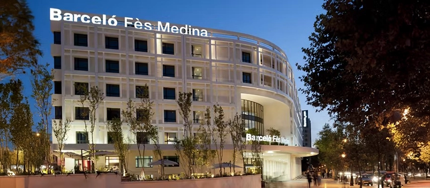 Evening view of Barceló Fès Medina with its modern white façade illuminated against the city skyline.