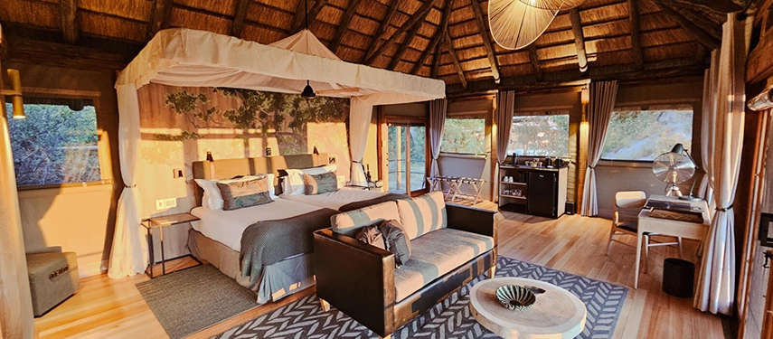 Spacious safari tent with king bed, lounge area, and natural wood finishes at Kanana Camp.
