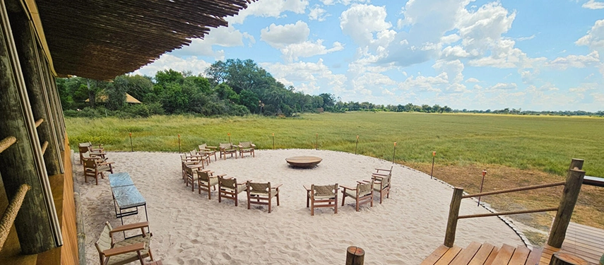 Sandy outdoor fire pit seating area at Kanana Camp overlooking open grasslands.