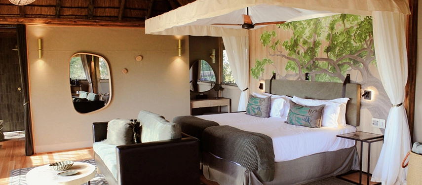 Stylish safari tent bedroom at Kanana Camp featuring hand-painted wall art and soft neutral tones.