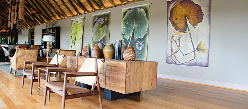 Lounge area at Kanana Camp featuring contemporary African decor and botanical artwork on the wall.