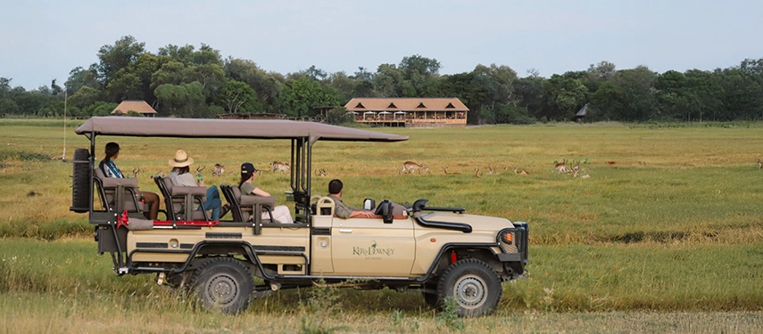 Guests on a game drive vehicle scanning the floodplain for wildlife in front of Kanana Camp.