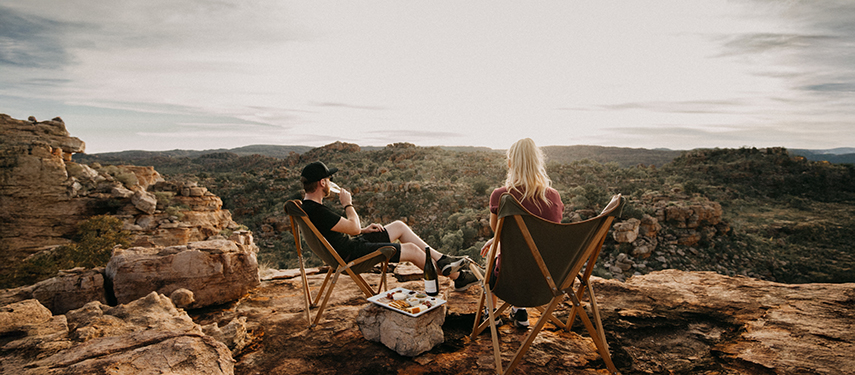 Couple sharing a picnic overlooking rugged outback landscapes