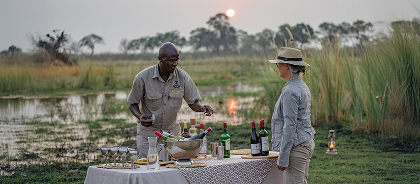 Guide preparing sundowners beside the water at Cha Cha Metsi.