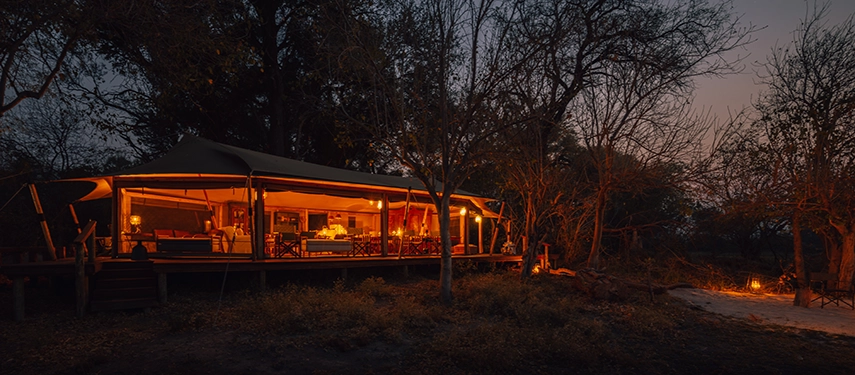Main tent at Cha Cha Metsi glowing warmly at dusk beside the firepit.