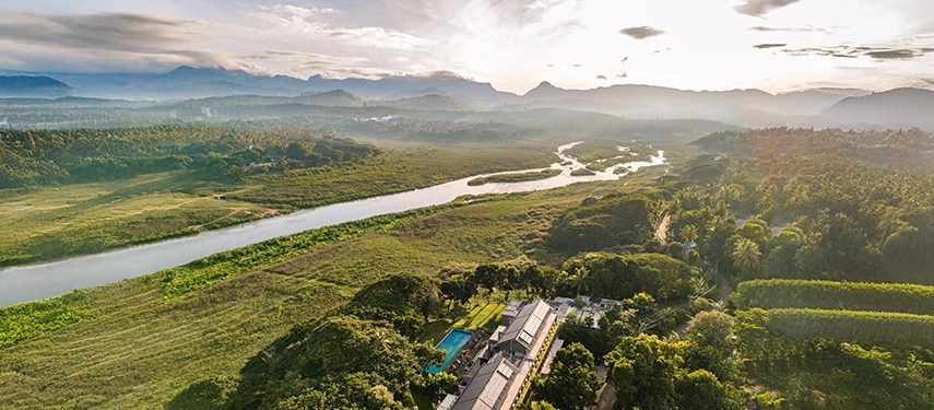 A golden sunrise reveals Jetwing Kandy Gallery nestled amid river plains and mountain silhouettes in the heart of Kandy’s landscape.