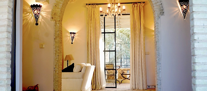 Elegant arched doorway leading to a bright salon at Dar Tozeur with chandeliers and terrace views.