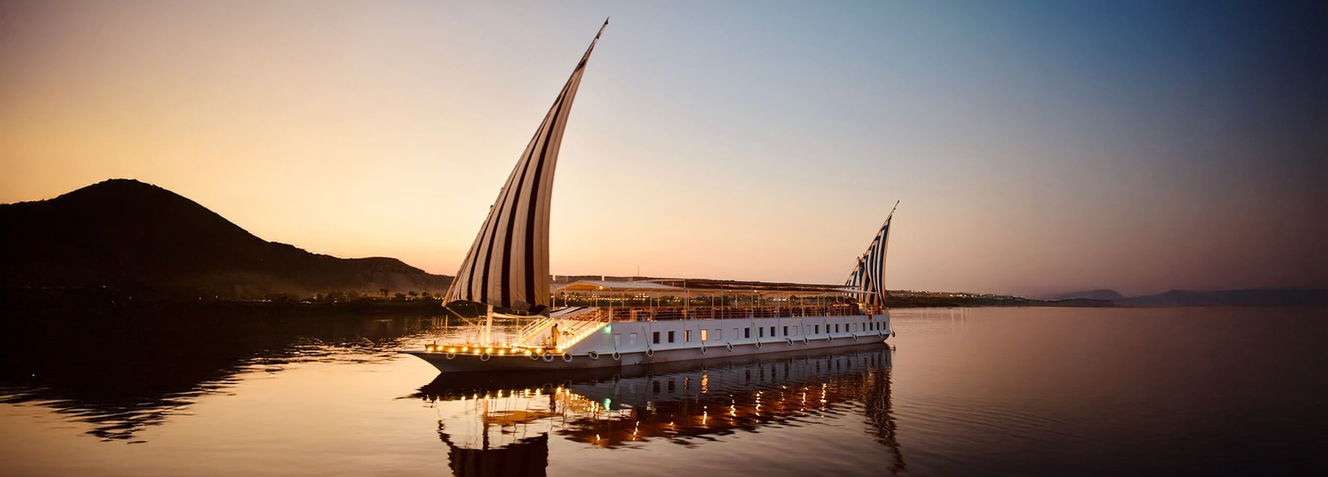 A Dahabiya drifting down the Nile River, Egypt, at sunset