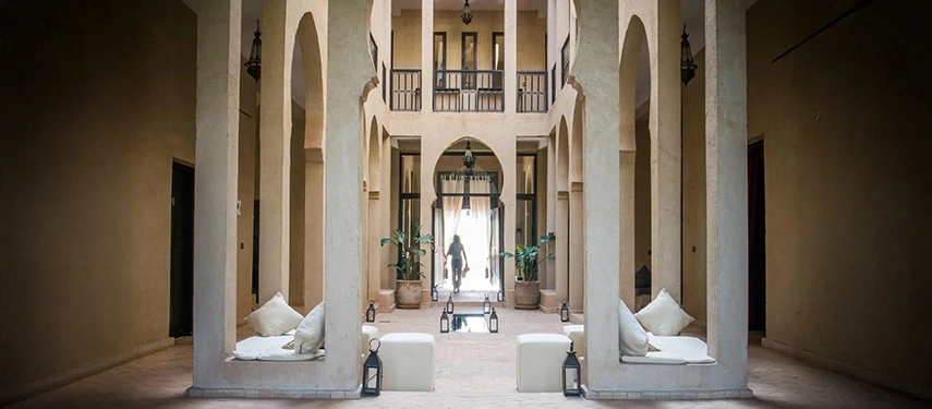 Spacious arched courtyard with white seating, lanterns, and natural light streaming through.