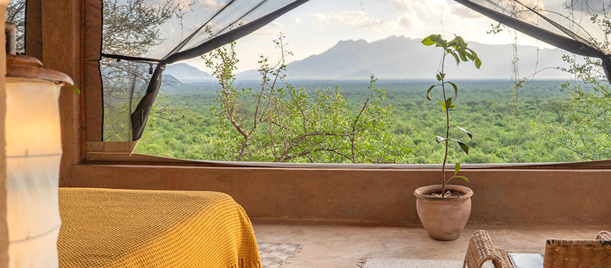Warm-toned bedroom interior in Reteti House with panoramic views through mesh-framed windows.
