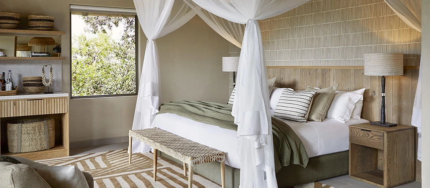 Luxurious superior chalet bedroom at Londolozi Founders Camp with four-poster bed and stylish earthy décor.