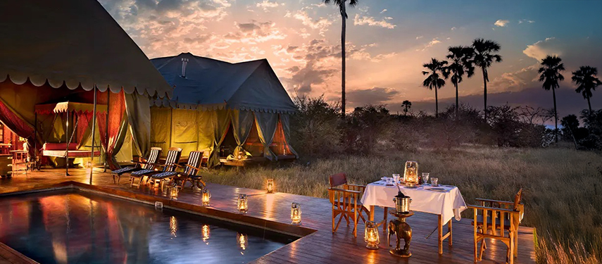 Romantic outdoor dining and lantern-lit poolside seating at Jack’s Private Camp as the sun sets.