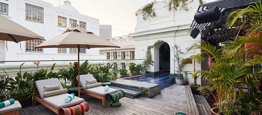Rooftop deck at Gorgeous George with pool, sun loungers, and urban garden surroundings.