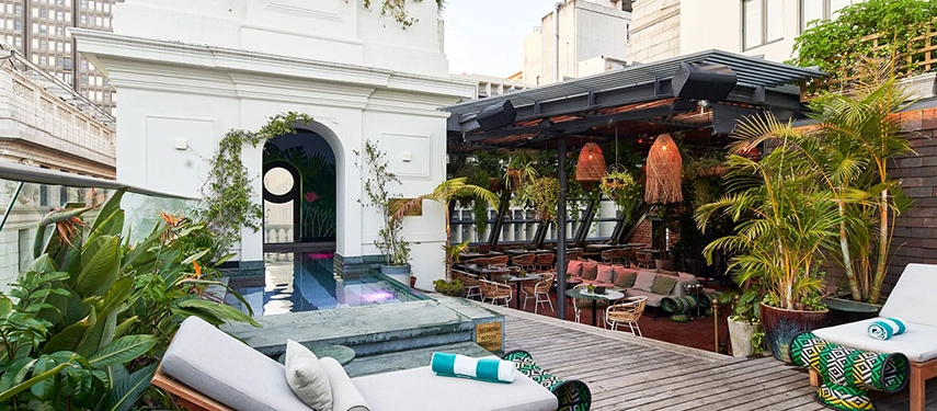 Poolside relaxation area with lush plants and city views at Gorgeous George.
