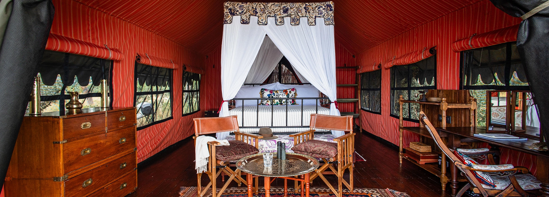 Elegant guest tent interior with a four-poster bed and vintage-style furnishings.
