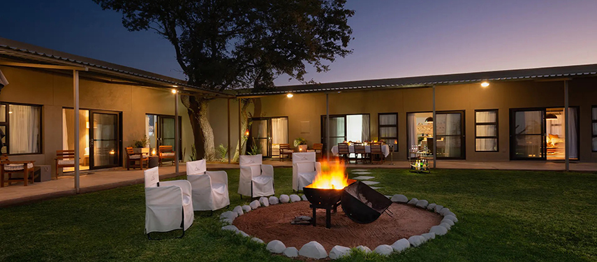 Cosy courtyard at Safari House with firepit glowing warmly under the night sky.