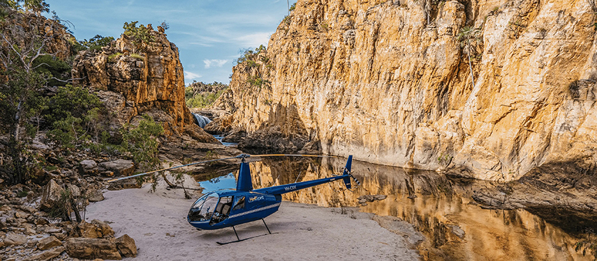 Helicopter parked beside a river in a dramatic gorge