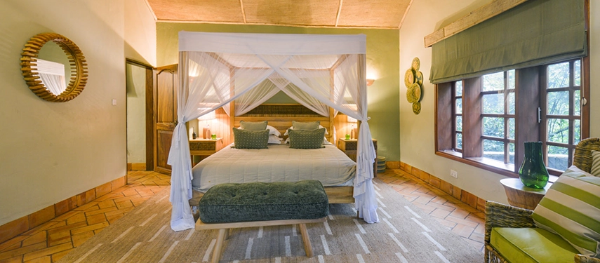 Cosy double room in the Honeymoon Cottage at Primate Lodge, styled with earthy tones, wooden furnishings, and canopy bed.