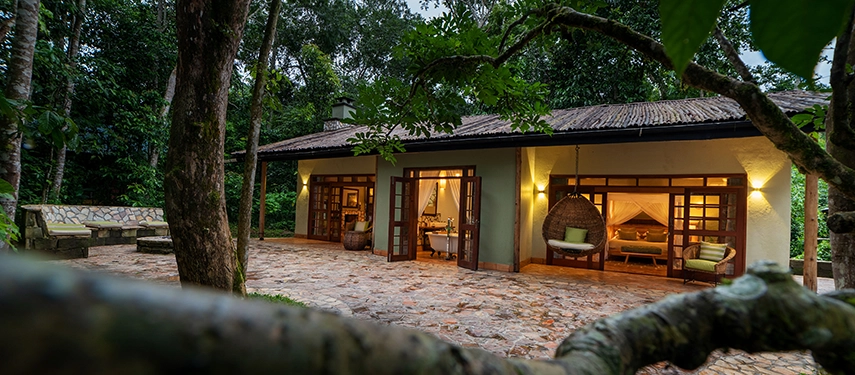 Private stone terrace and open plan design of the Honeymoon Cottage at Primate Lodge, surrounded by lush Kibale Forest greenery.