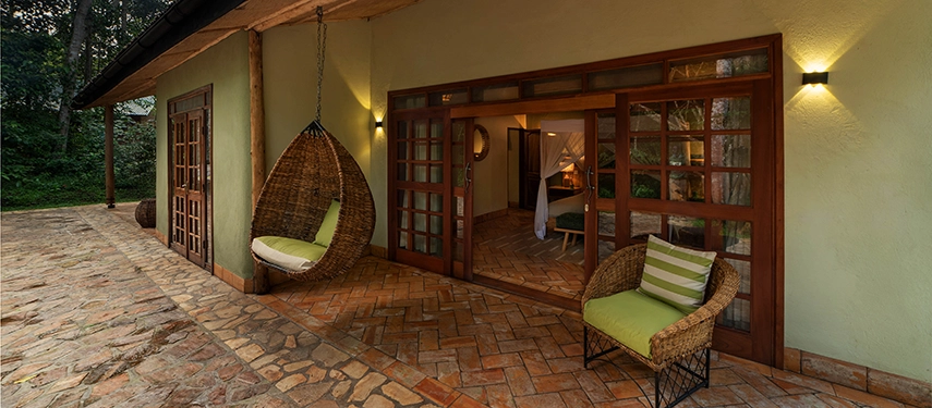 Romantic honeymoon suite with rustic design, soft lighting, and forest views at Primate Lodge Kibale, Uganda.